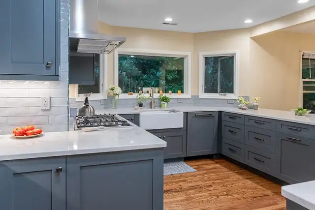 Aging-in-place kitchen with slate blue shaker cabinets, farmhouse sink, white quartz counters and a window over the sink