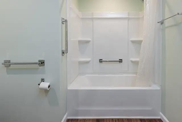 Roll-under bathroom sink with granite top and open base for wheelchair access beside a paneled door