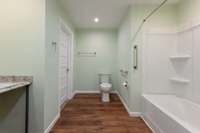 Accessible bathroom in Montreat, NC with tub surround, grab bars, sage green walls and wood-look floor