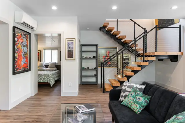 Whole-home remodel and addition in Greenville, SC with floating wood stair treads, cable railing and a guest bedroom off the living room