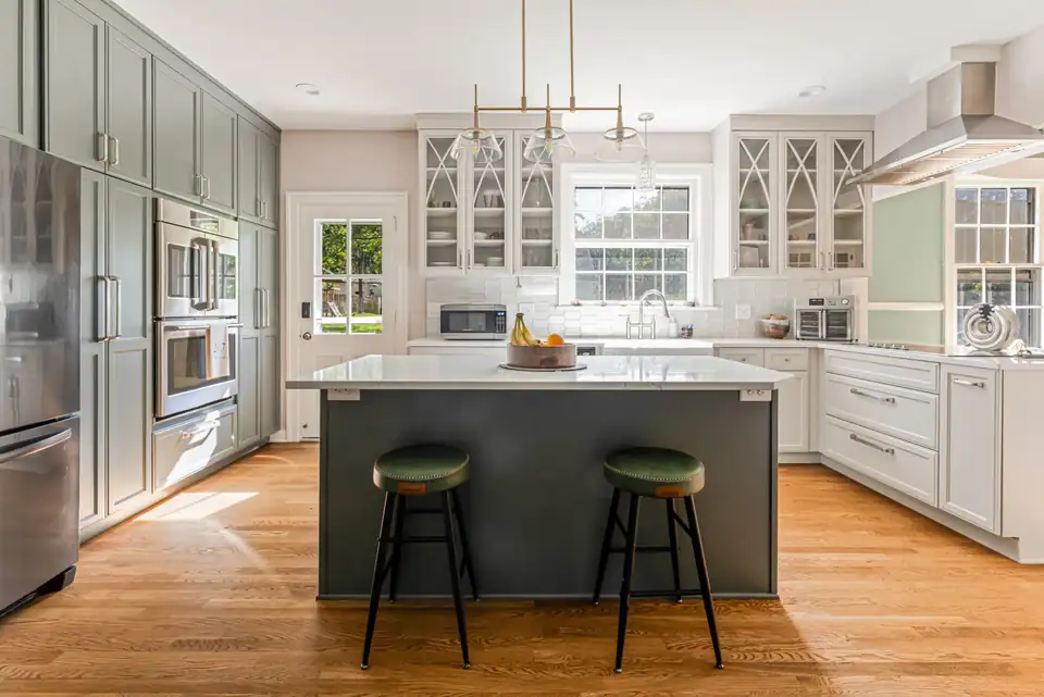 Kitchen remodeling Asheville NC area: Black Mountain kitchen with a dark green island, white quartz top, glass-front upper cabinets and brass pendant lights