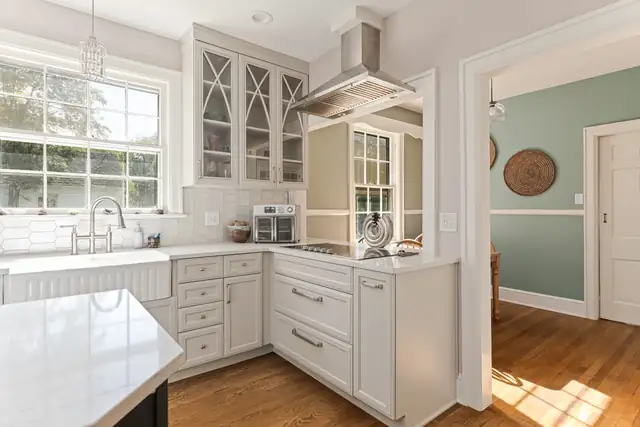 Black Mountain kitchen with farmhouse sink under a double window, glass-front upper cabinets and a stainless range hood
