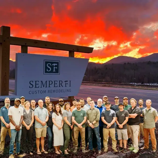Semper Fi Custom Remodeling crew standing beside the company sign at sunset with the Blue Ridge Mountains behind them
